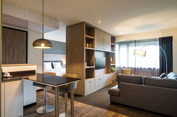 a living room filled with furniture and a flat screen tv mounted to a wall next to a kitchen