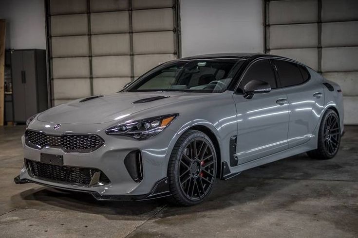 the front end of a silver car in a garage with two doors on one side