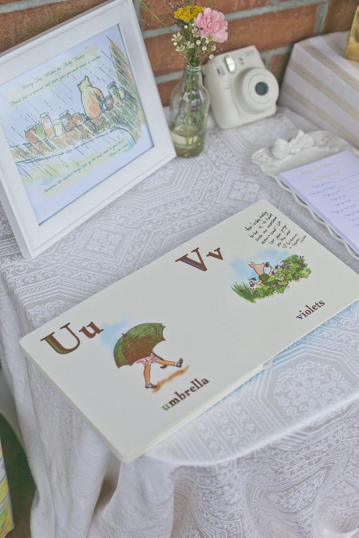 a table topped with cards and pictures next to a vase filled with flowers on top of a white table cloth