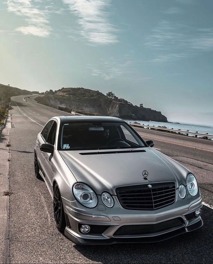 a silver mercedes cls parked on the side of the road next to the ocean