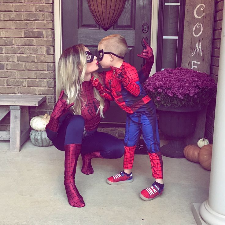 two children dressed up as spider - man kissing each other on the front door steps