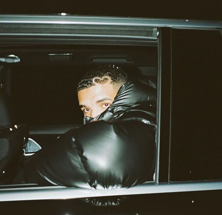 a man in black leather gloves leaning out the back door of a car at night