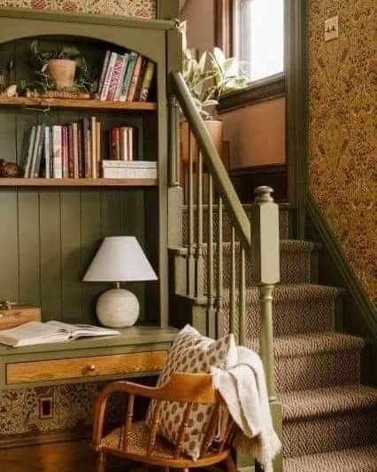 a chair sitting in front of a bookshelf next to a stair case