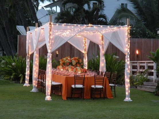 an outdoor table set up with lights on the top and chairs around it for a formal function