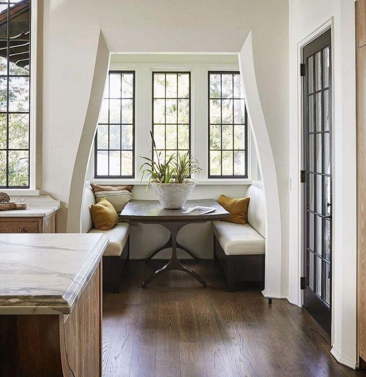 a kitchen with white walls and wood flooring next to a breakfast nook area