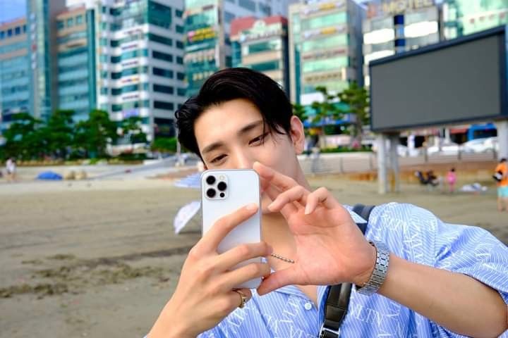 a man taking a selfie with his cell phone in front of the cityscape