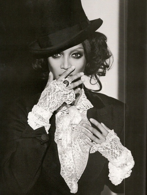 a black and white photo of a woman wearing a top hat, gloves and lace