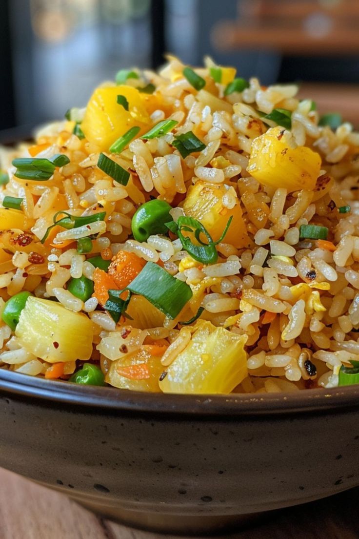 a bowl filled with rice and vegetables on top of a wooden table