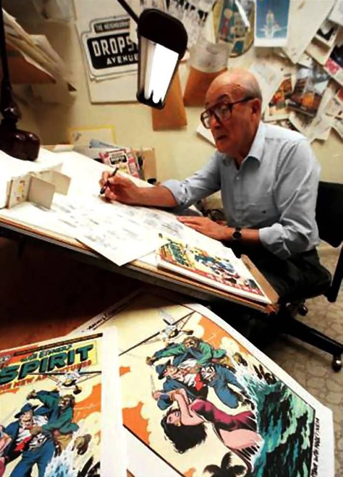 an older man sitting at a desk with comic books