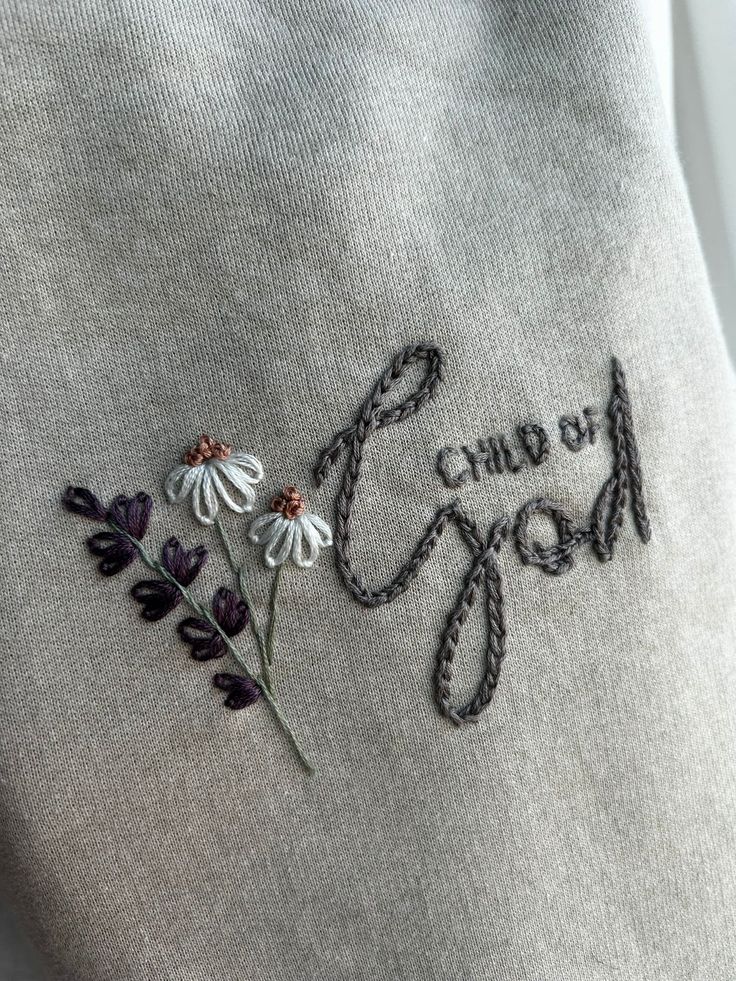 a close up of a sweater with embroidered flowers on it and the words group of mom written in cursive writing