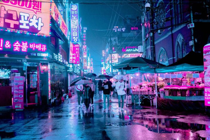 people are walking down the street in the rain with umbrellas on a rainy night