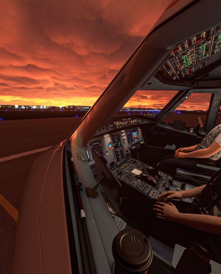 two pilots are sitting in the cockpit of an airplane at sunset or dawn, looking out into the distance