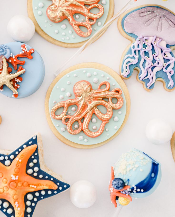 decorated cookies with sea animals and starfishs on a white tablecloth next to decorations