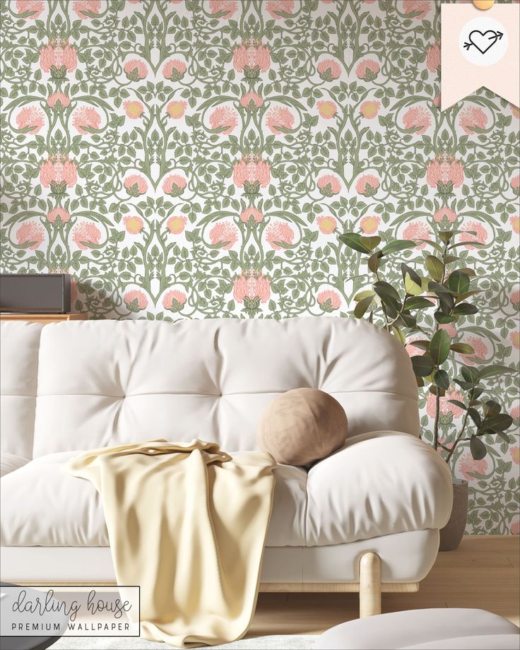 a white couch sitting in front of a wall with pink and green flowers on it