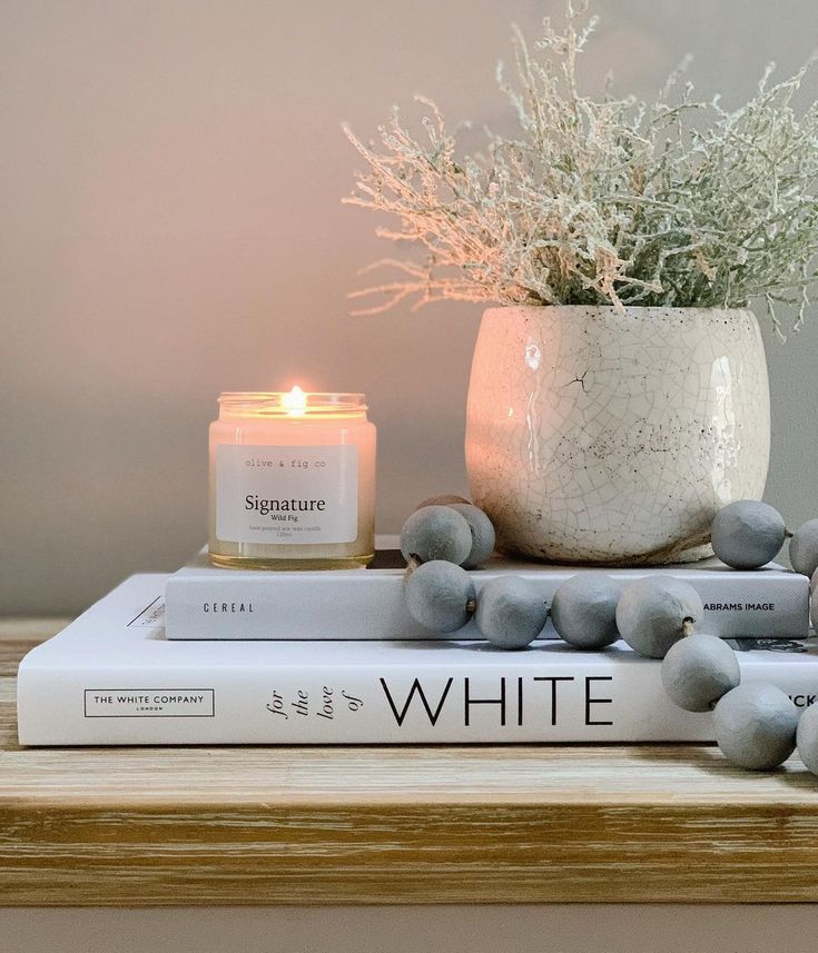 a candle sits on top of two books with flowers in a vase behind it,