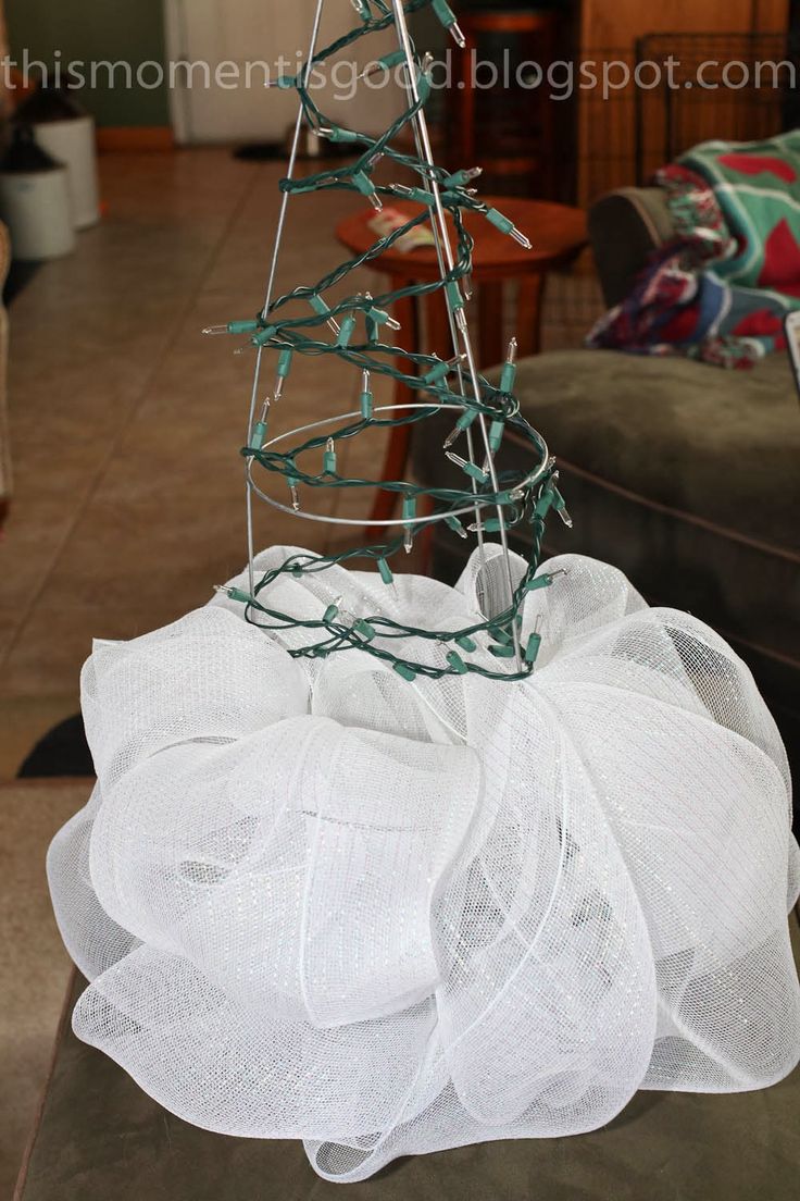 a christmas tree made out of wire and mesh is sitting on a table in the living room