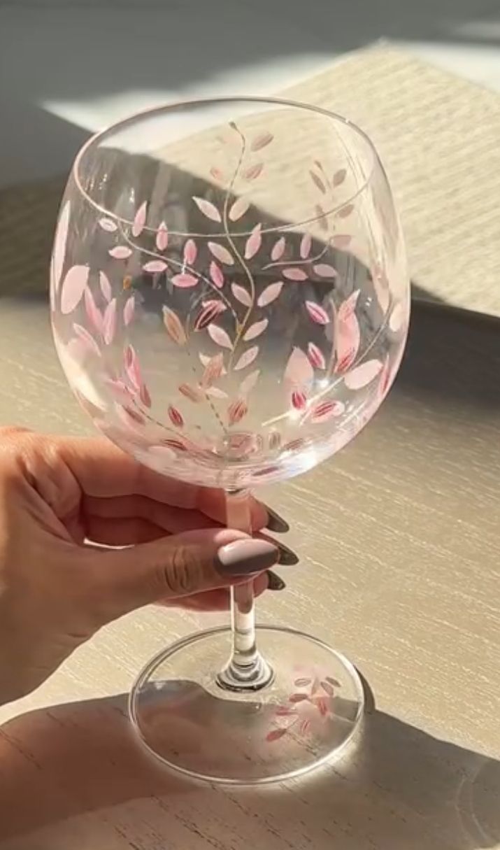 a woman holding a wine glass with pink flowers on it