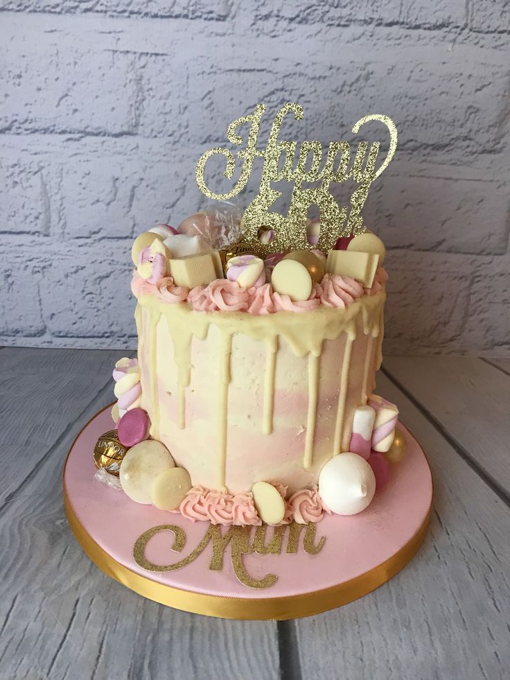 a pink and gold birthday cake sitting on top of a table