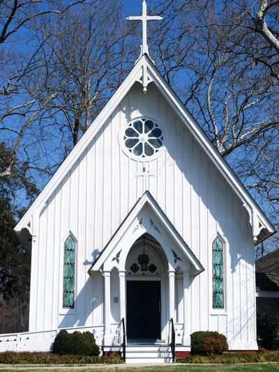 a white church with stained glass windows and a cross on the front door is shown