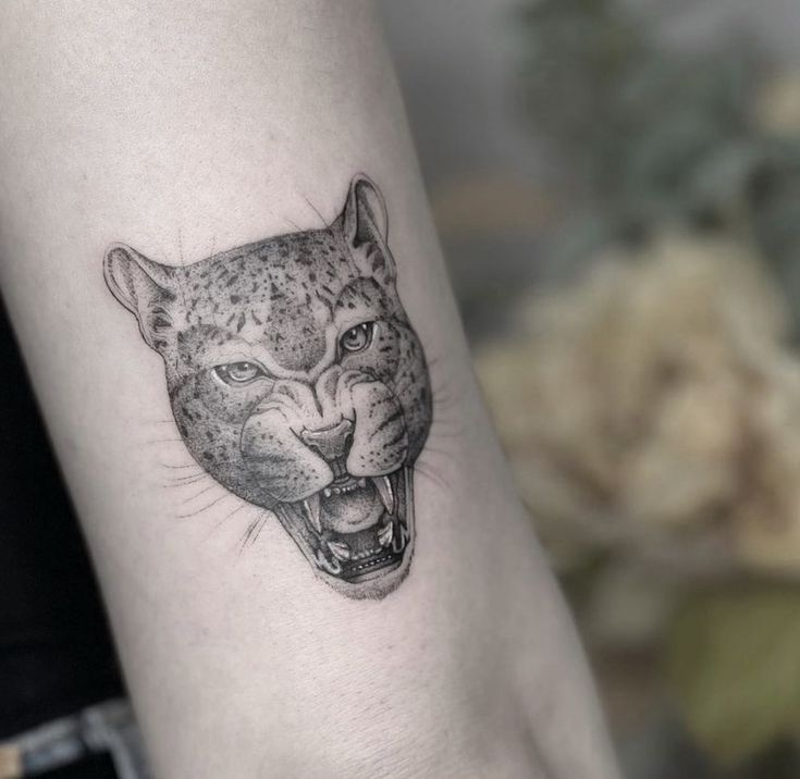 a black and white photo of a leopard's head on the left inner arm