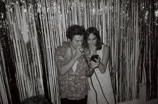 two people standing next to each other in front of a curtain with sequins on it