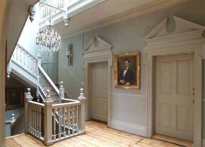 an entry way with stairs, chandelier and painting on the wall in front of it