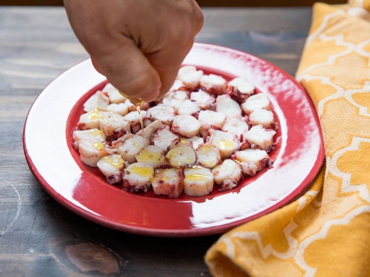 a person is picking up some food from a red and white plate on a wooden table