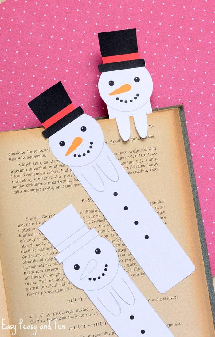 an open book with two snowmen cut out of paper and one is sitting on top of it