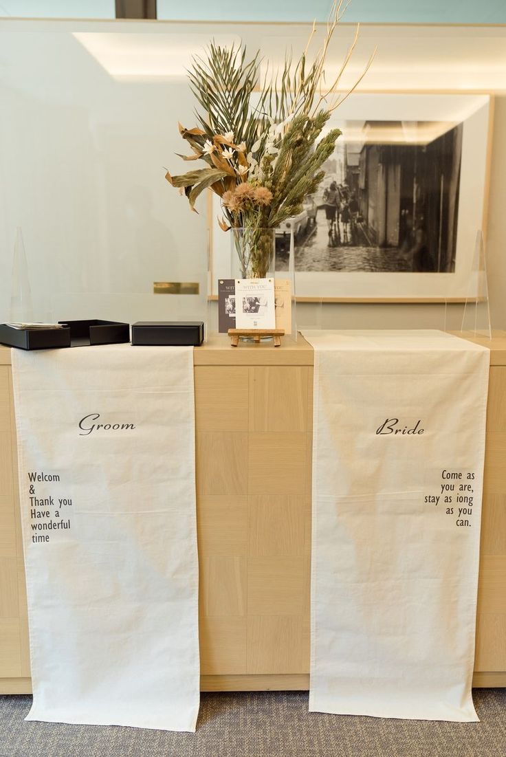 two white linens with black writing on them sitting next to each other in front of a mirror