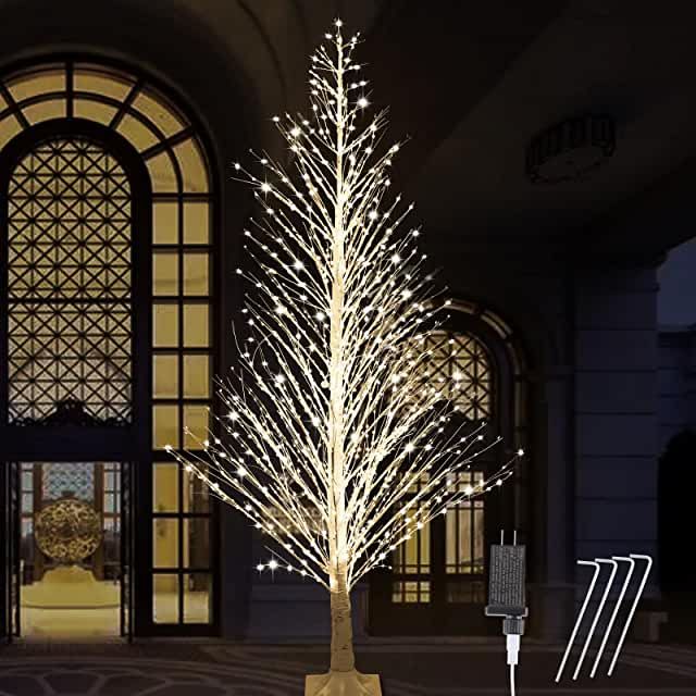 a lighted christmas tree in front of a building with an open door and window behind it