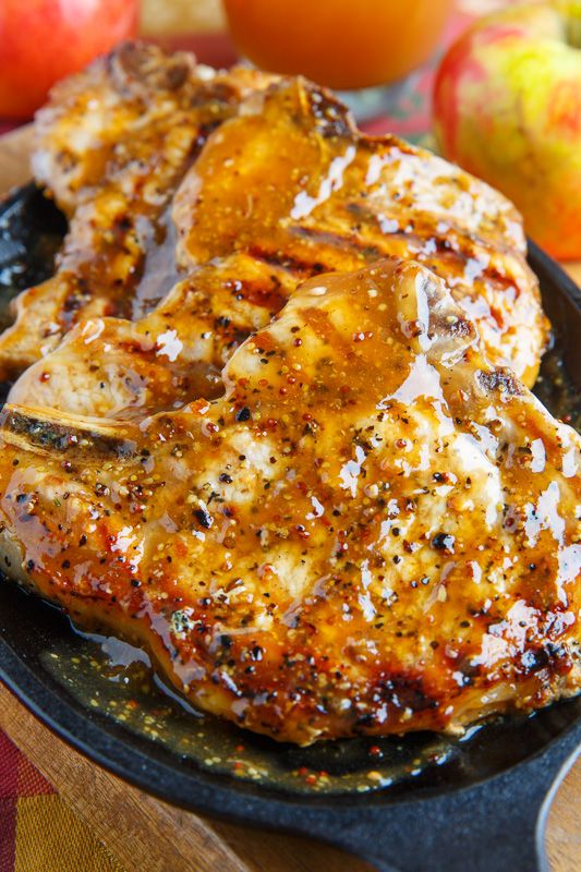 a close up of meat on a plate with apples in the background