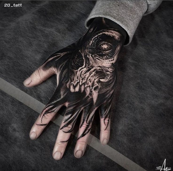 a man's hand with black and white tattoos on it, which has an image of a skull in the middle