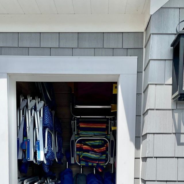 an open garage door with several pairs of shoes and umbrellas on the shelf in it