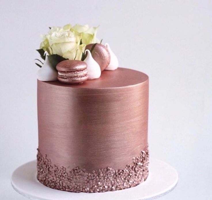 a pink cake with macaroons and flowers on top