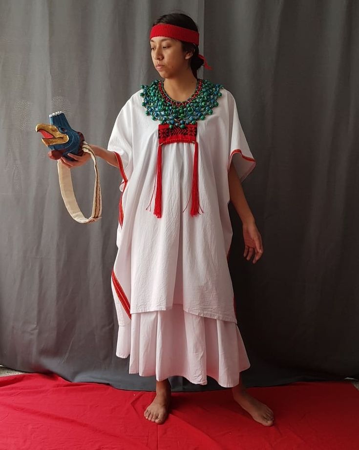 a woman wearing a white dress and red headband holding a pair of blue shoes