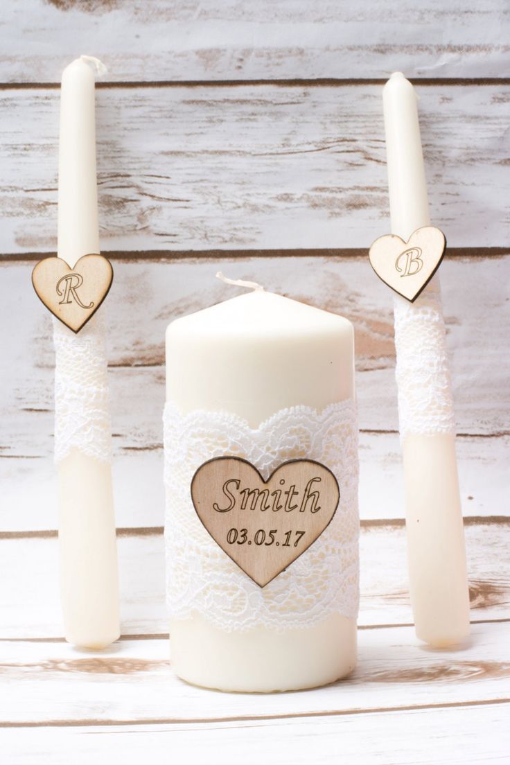 two candles with hearts on them sitting next to each other in front of a wooden background