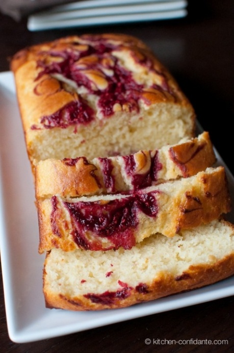 two slices of bread with raspberry toppings on a white plate