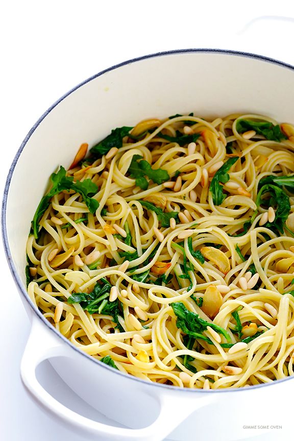 a white pot filled with pasta and spinach