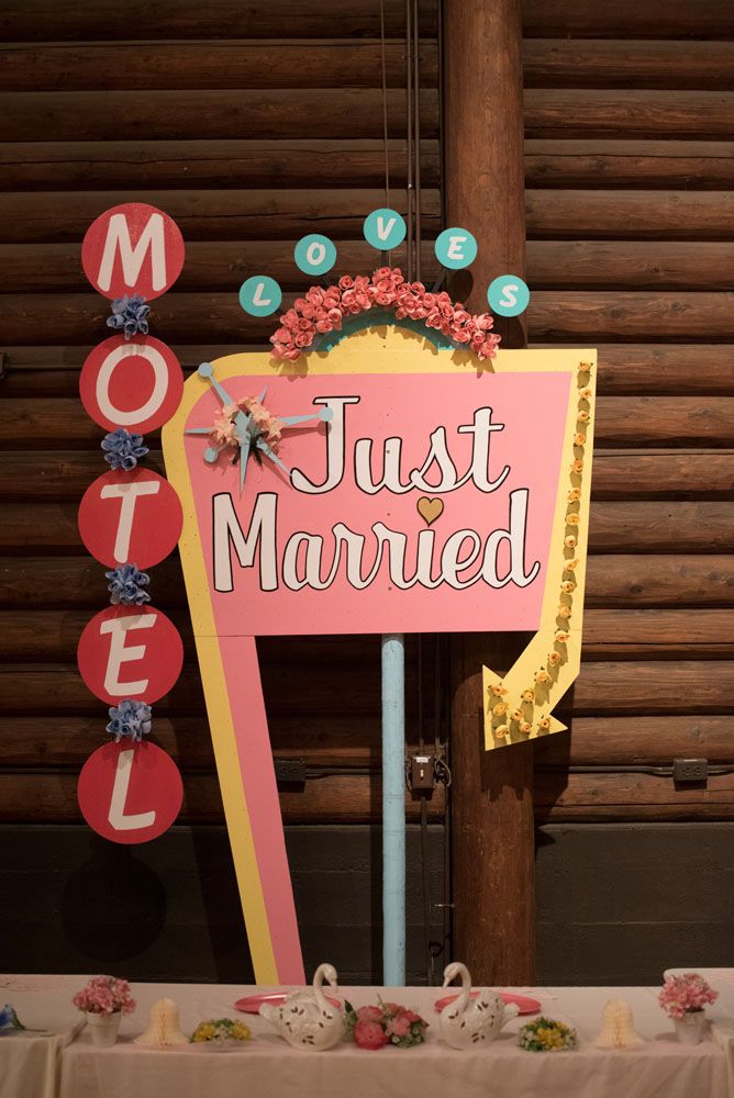 a pink sign that says just married next to a table with flowers and teapots