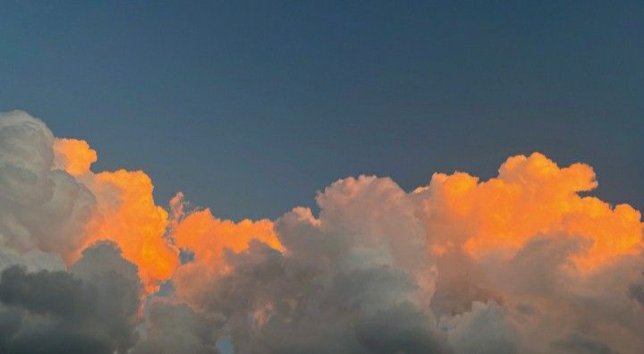 an airplane is flying through the clouds at sunset