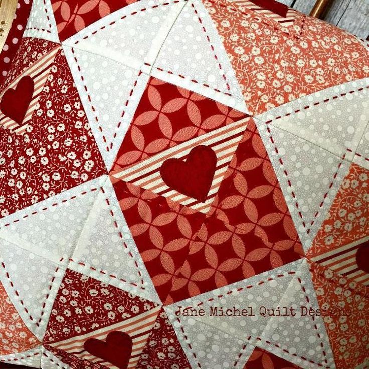 red and white patchwork quilt with heart on it's side, sitting on a wooden surface