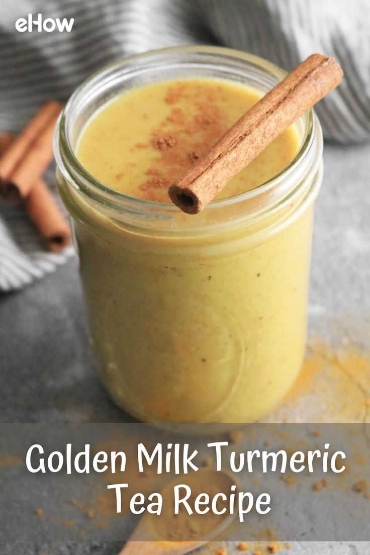 a glass jar filled with yellow liquid and cinnamon stick on top of it next to a wooden spoon