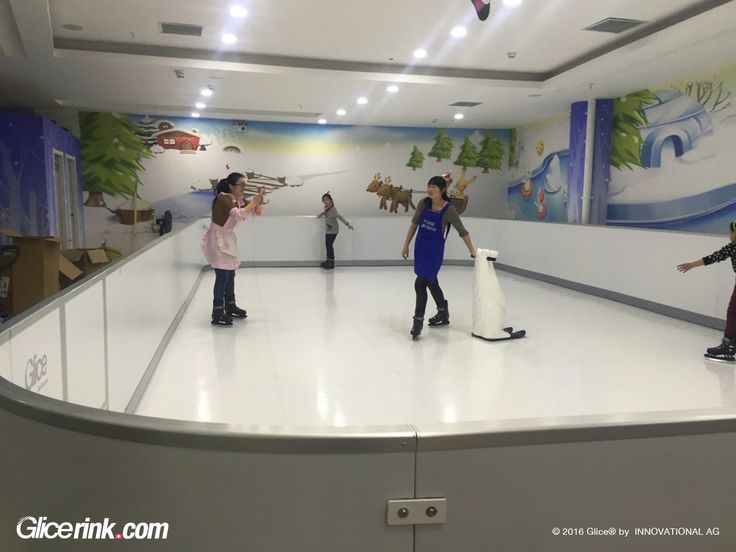 children are playing on an ice rink with fake snowmen and deers painted on the walls