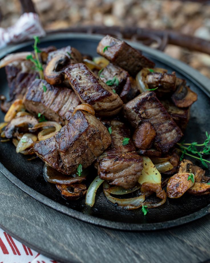 some meat and onions are on a black plate