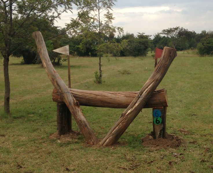 a wooden bench sitting in the middle of a field next to some trees and grass