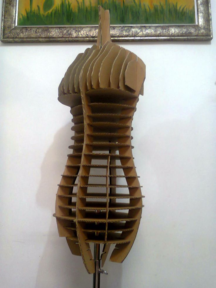 a sculpture made out of cardboard sitting in front of a painting