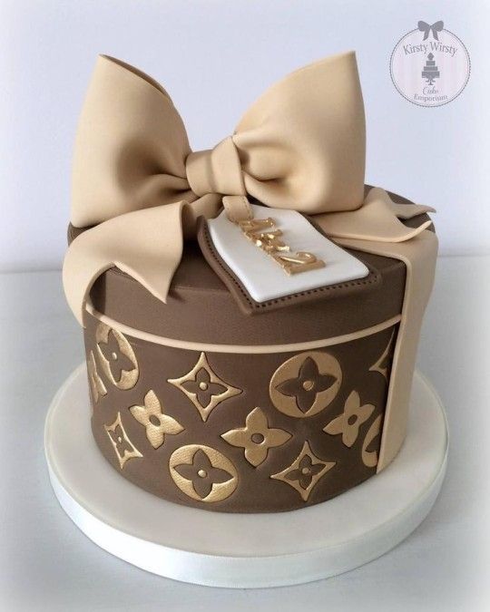 a cake decorated with gold and brown designs on top of a white platter topped with a bow