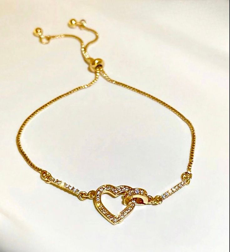 The 18kt gold plated heart bracelet is a symbol of love that will add a touch of romance to any outfit, at the center of the bracelet is a captivating heart adorned with shiny cubic zirconia that steals the spotlight. This bracelet is designed with a sliding mechanism that allows the wearer to easily adjust the bracelet's length to achieve a perfect fit. All our jewelry comes in a gift box Gold Cubic Zirconia Heart Bracelet For Valentine's Day, Valentine's Day Gift Heart Bracelet In Cubic Zirconia, Cubic Zirconia Heart Bracelet For Valentine's Day, Gold Promise Bracelet For Valentine's Day, Gold Heart Charm Bracelet With Cubic Zirconia, Elegant Adjustable Open Heart Bracelet, Dainty Cubic Zirconia Heart Bracelet, Dainty Heart-shaped Cubic Zirconia Bracelet, Elegant Heart Bracelet With Adjustable Chain For Mother's Day