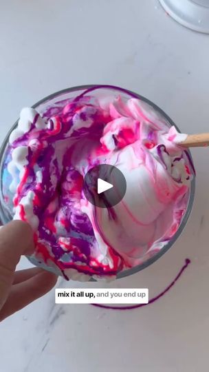 someone is holding a spoon over a bowl of food that has pink and purple paint on it