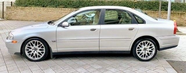 a silver car parked in front of a brick wall